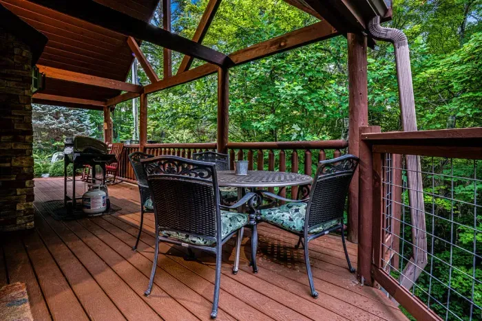 Covered forest-view deck with outdoor dining and grill