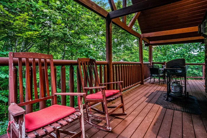 Covered forest-view deck with rocking chairs and outdoor dining