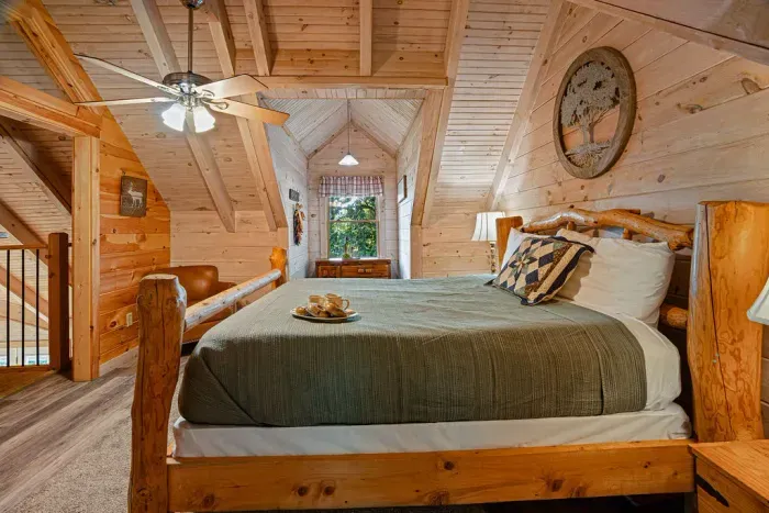 Cozy loft bedroom with rustic log bed and warm wood cabin charm