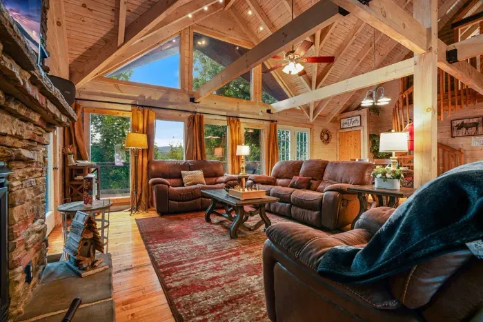 Cozy lodge-style living room with vaulted ceilings, fireplace, and views
