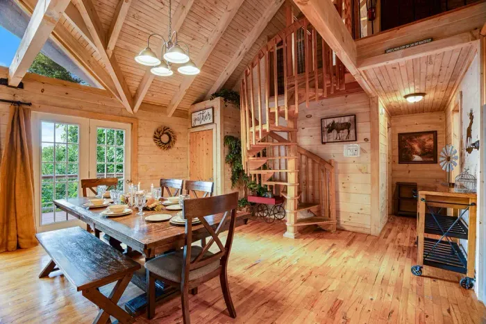 Rustic vaulted dining space with loft, spiral stairs, and natural light
