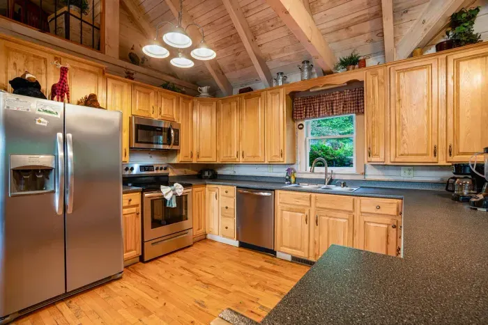 Rustic full kitchen with vaulted ceilings and stainless steel appliances
