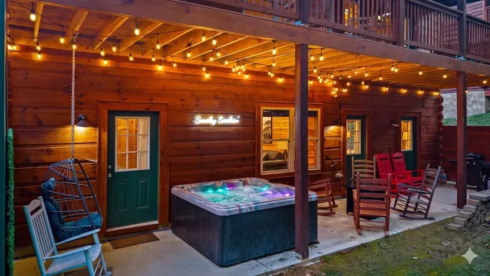 Cozy covered patio with hot tub, string lights, and rocking chairs