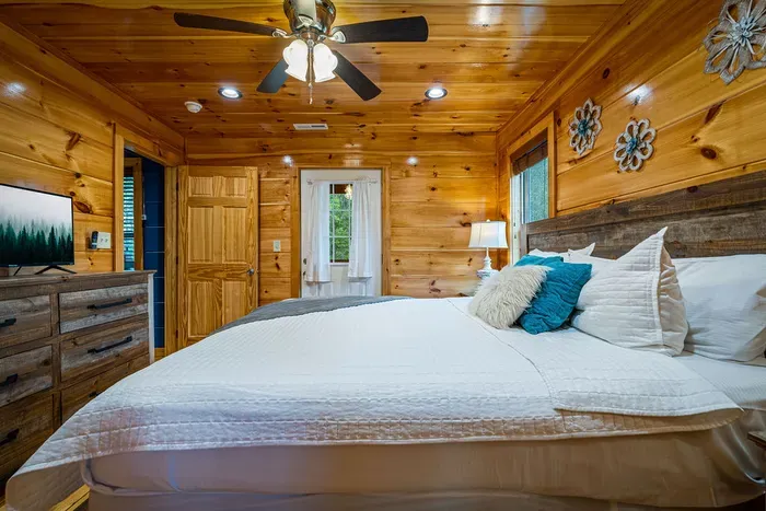 Cozy cabin bedroom with king bed, TV, and warm wood interiors.