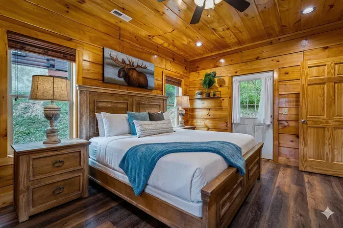 Cozy cabin bedroom with king bed, wood interiors, and forest-view deck.