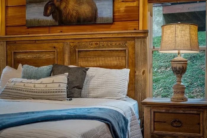 Rustic cabin bedroom with plush bedding, artful touches, and warm lamplight