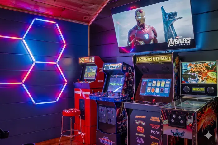 Neon-lit arcade lounge with pinball, classic cabinets, and big-screen fun