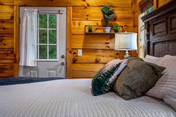 Cozy log cabin bedroom with outdoor door, plants, and rustic charm