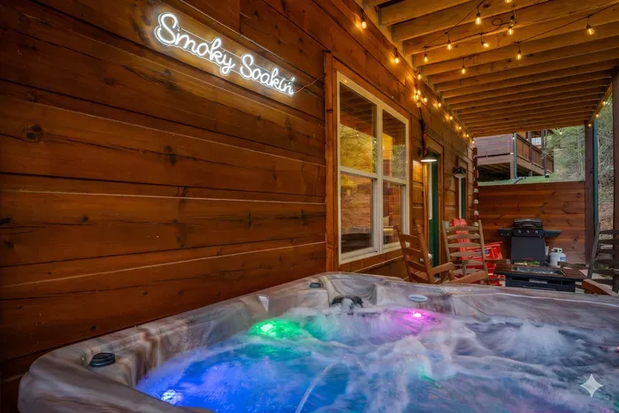 Cozy covered deck: LED hot tub, string lights, rockers, and grill.