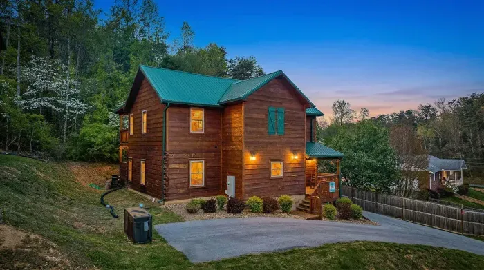 Rustic cabin at dusk with porch, ample parking, and wooded views