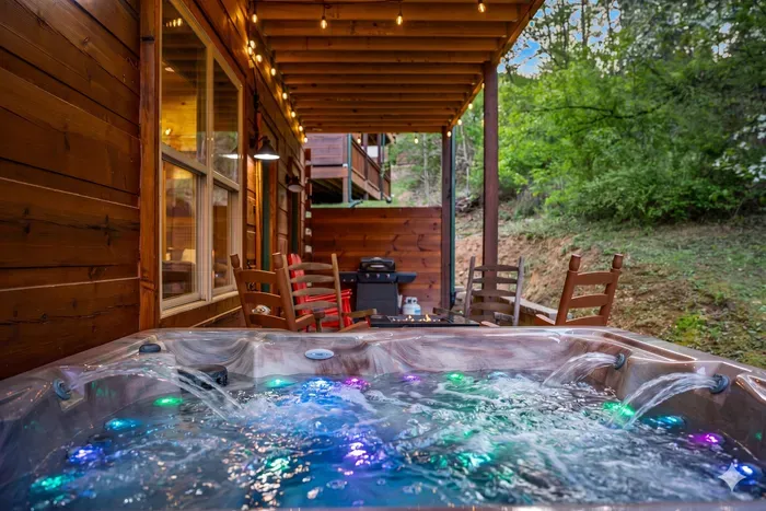 Covered deck oasis: LED hot tub, grill, and rocking chairs by the woods