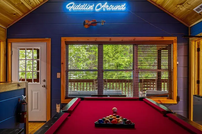 Enjoy forest views shooting pool under the cabin branded neon sign and fiddle decor