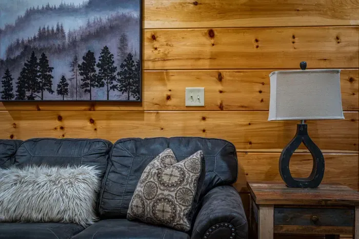 Cozy cabin lounge: leather sofa, warm wood walls, modern lamp
