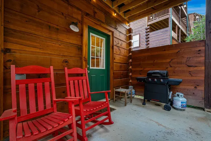 Cozy covered patio with red rockers and propane grill for easy BBQs