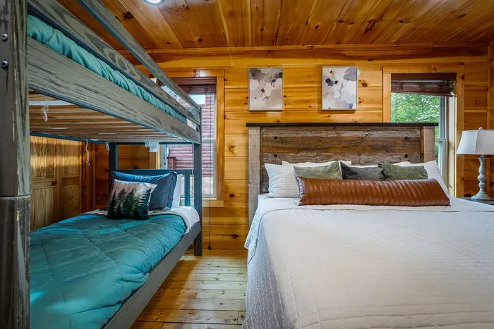Cozy cabin bedroom with queen + bunks, wood walls & nature views