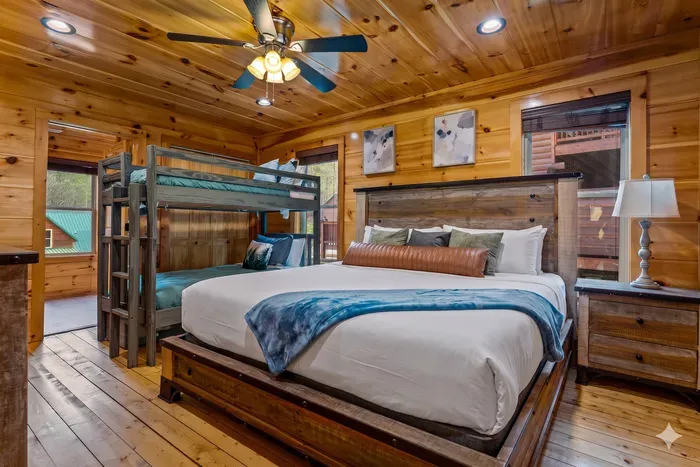 Cozy cabin suite with king bed, bunks, and warm knotty-pine charm.