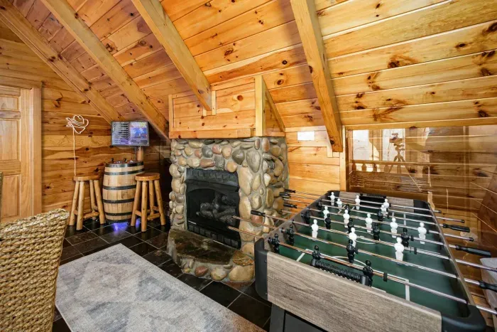 Loft with fireplace, foosball, additional whiskey barrel arcade, and game table 