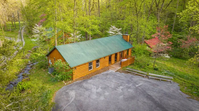 Secluded creekside log cabin with porch, parking, and forest views