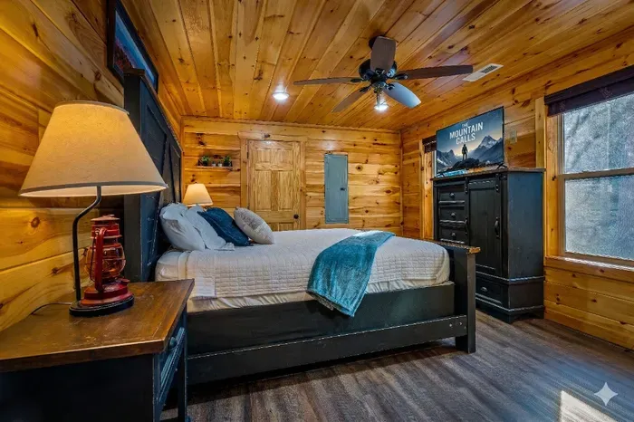 Cozy pine cabin bedroom with king bed, HDTV and forest-view windows