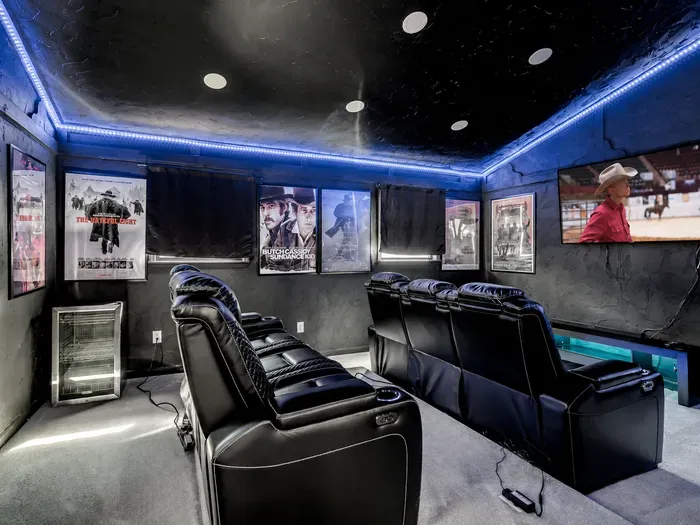 Private home theater with recliners, movie posters, and ambient LED lighting