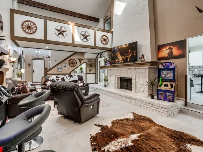 Spacious Western-style living room with fireplace, TV, and fun arcade game