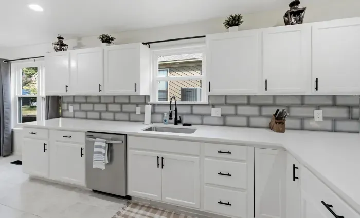 Bright modern kitchen with white cabinets, long counters, and natural light
