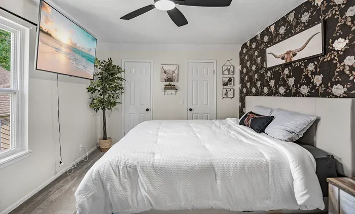Cozy stylish bedroom with king bed, TV, and elegant floral accent wall