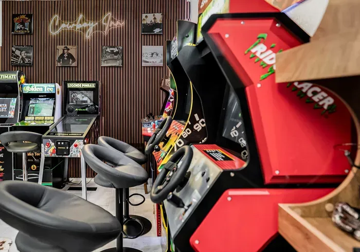 Retro arcade game room with racing games, pinball, and lounge seating