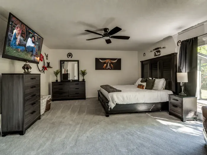 Spacious king bedroom with dark wood furnishings, TV, and warm rustic style