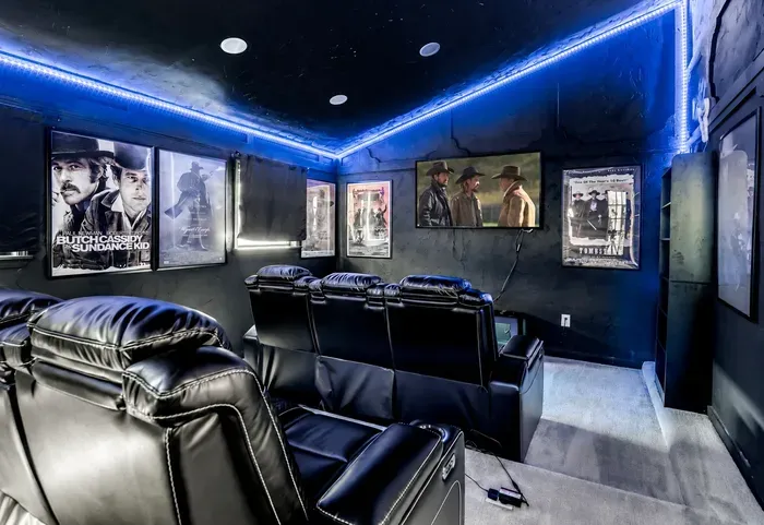 Private home theater with recliners, movie posters, and LED mood lighting