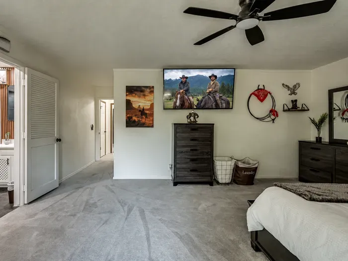 Spacious western-inspired bedroom with TV, ceiling fan, and cozy style