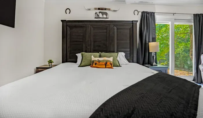 Cozy rustic bedroom with king bed, natural light, and peaceful wooded views