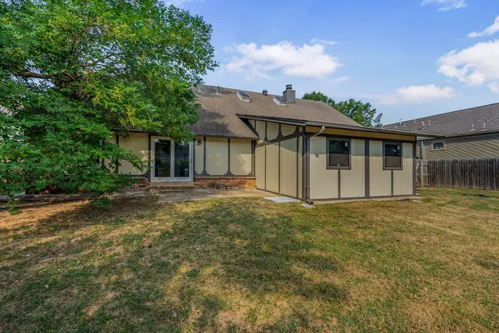 Spacious fenced backyard with mature shade tree and rear patio access
