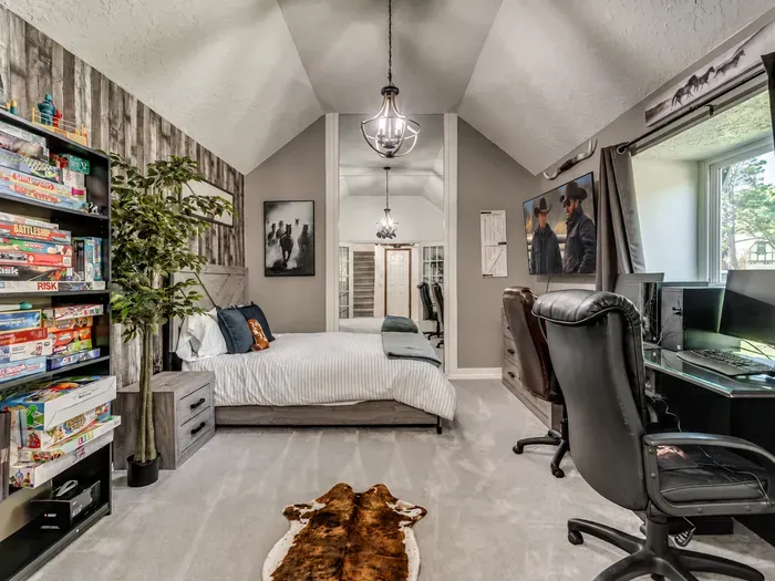 Cozy loft bedroom with workspace, natural light, and fun game collection