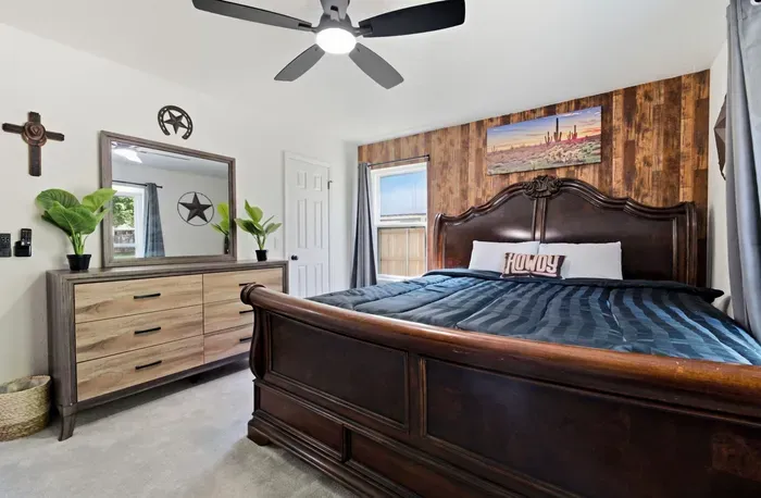 Rustic king bedroom with wood accents, ceiling fan, and warm Western charm