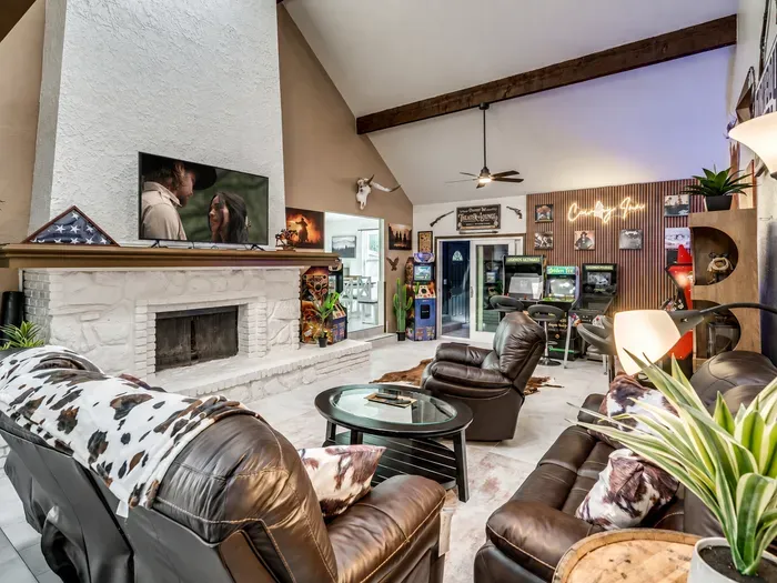Vaulted great room with stone fireplace, leather seating & arcade games