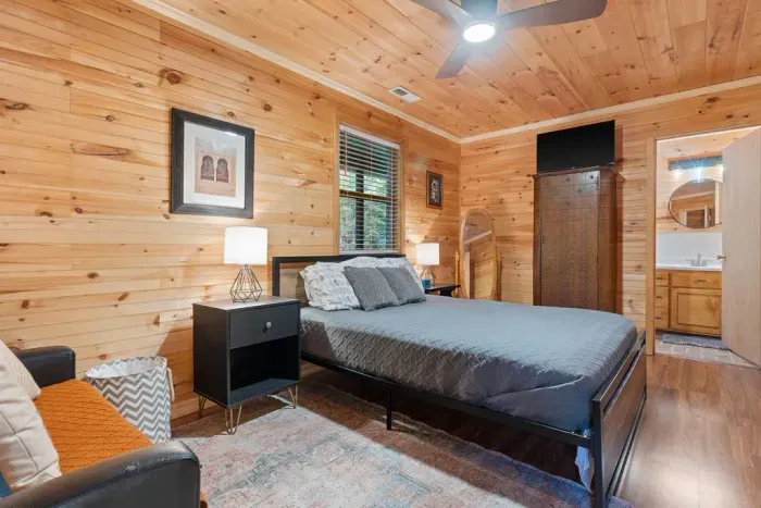 Cozy wood-paneled bedroom with ensuite bath and cabin charm