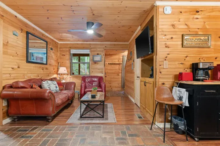 Cozy wood-paneled cabin lounge with leather seating, TV, and coffee bar