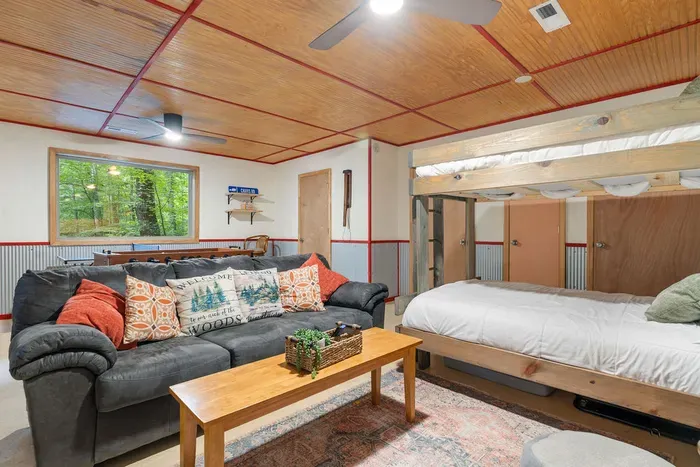 Cozy cabin-style bunk room with sectional seating and peaceful forest views