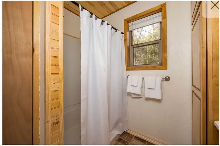Cozy cabin bath with natural light, fresh towels & tub/shower