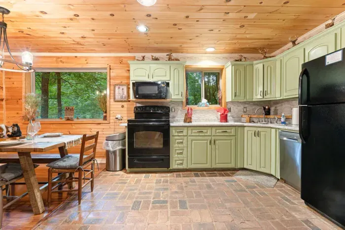 Cozy cabin kitchen with wooded views, rustic dining, and full-size appliances