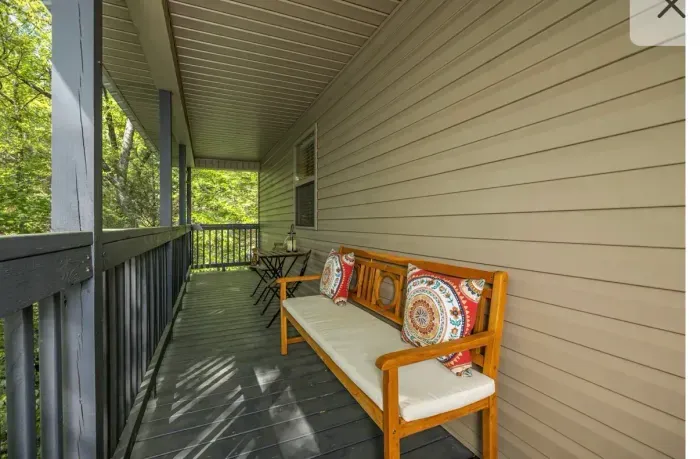 Shaded porch with bench & bistro set, serene tree-lined view