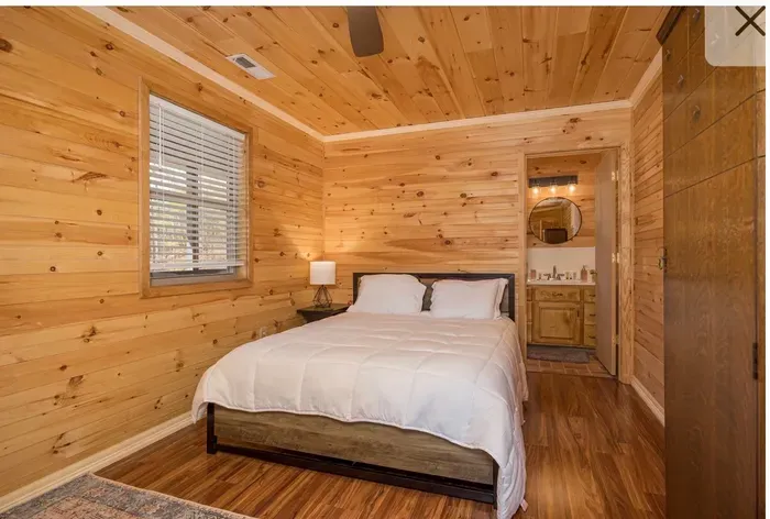 Cozy wood-paneled bedroom with queen bed and ensuite bath