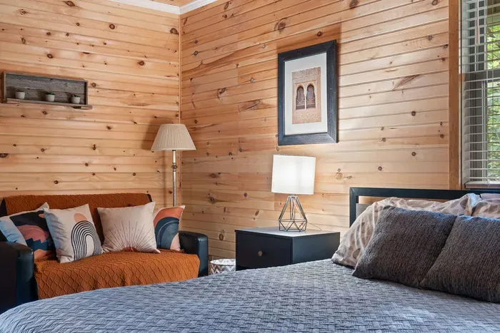 Cozy wood-paneled bedroom with lounge seating and warm cabin charm