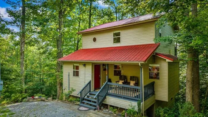 Cozy woodland cabin with red metal roof and inviting covered porch