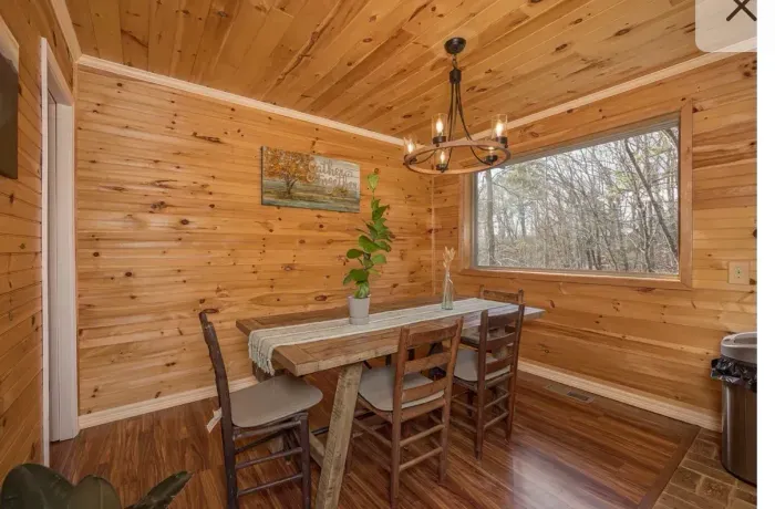 Cozy cabin dining nook with woodland view and rustic chandelier