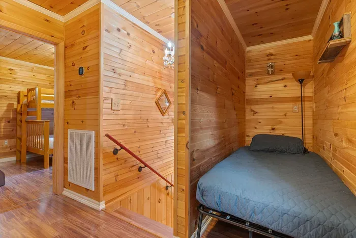 Cozy wood-lined sleeping nook near bunk room in a warm rustic cabin