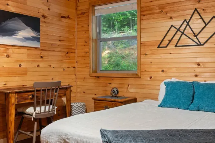 Cozy wood-paneled bedroom with forest views and a handy workspace