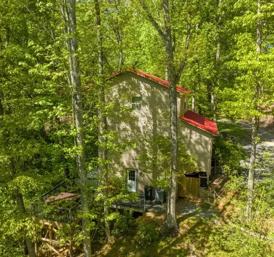 Secluded forest cabin with red roof and spacious deck with hot tub