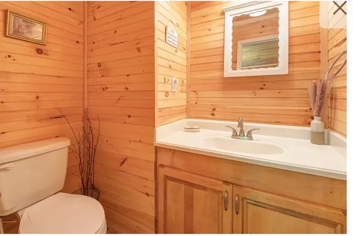 Cozy wood-paneled bath with clean vanity and rustic charm